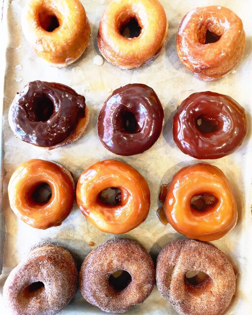 Selection of glazed doughnuts, vanilla, chocolate, caramel and cinnamon